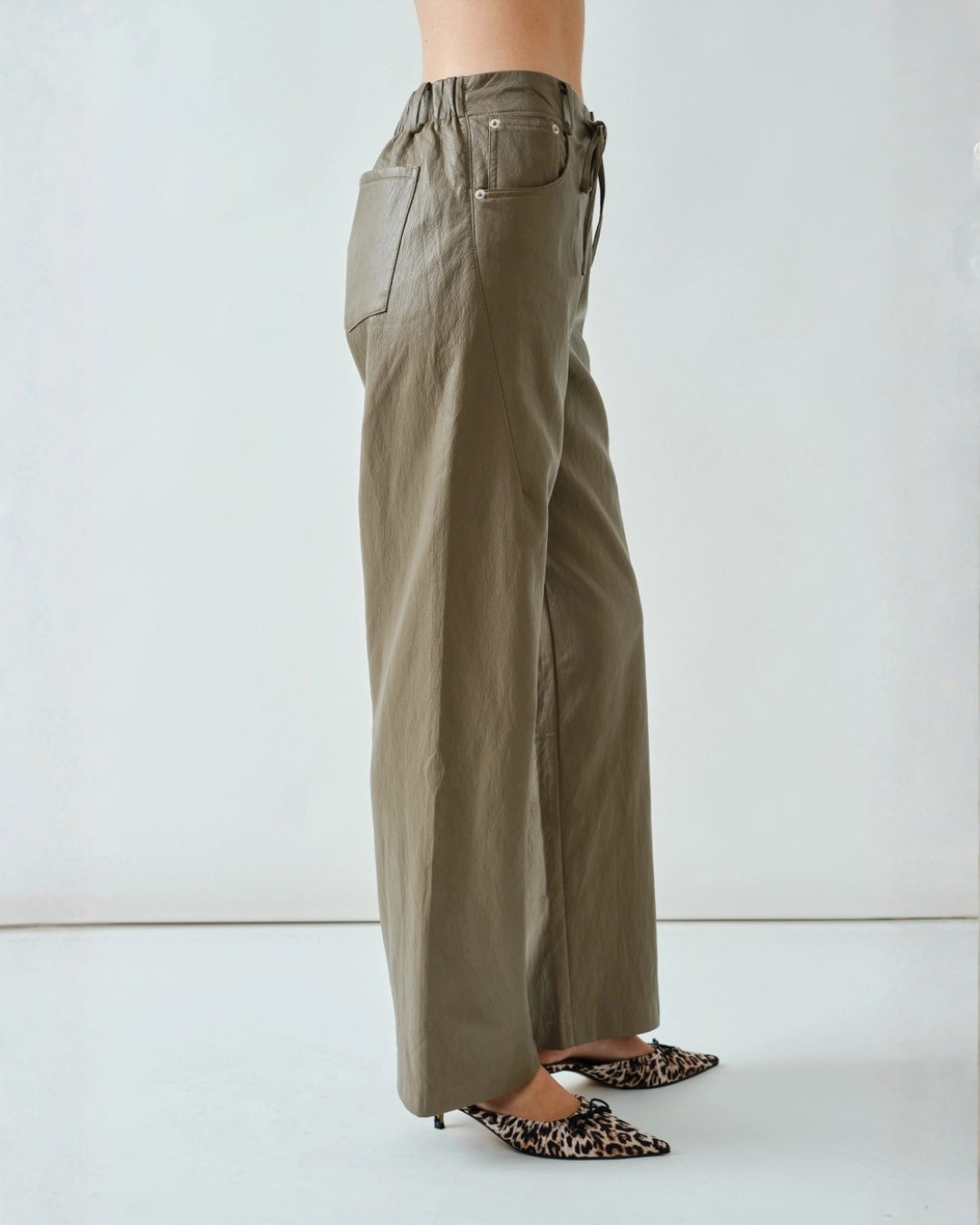 Minimalist soft-brown faux leather trousers featuring a modern fit, subtle texture, and comfortable everyday wear.